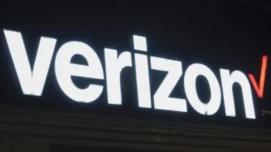 Illuminated Verizon logo on a building at night.