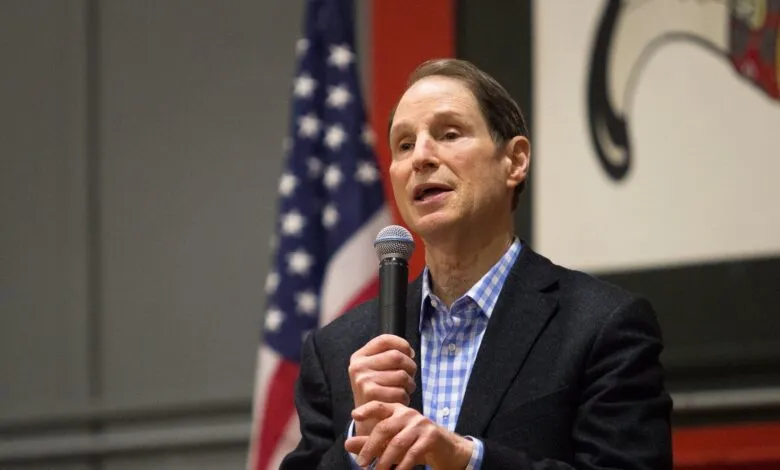 Senator Ron Wyden speaking at an event, holding a microphone.