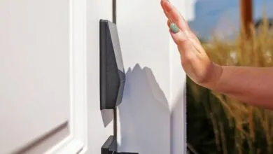 Hand approaching a sleek, black smart lock mounted on a white door. Modern home security.
