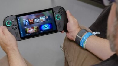 Person holding a handheld gaming device with a vibrant game library displayed on screen.