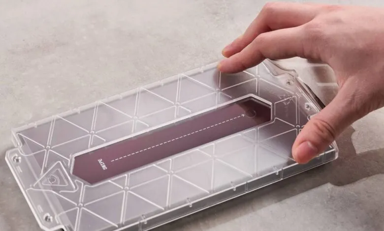 Hand inserting a dark purple card into a clear plastic case with a geometric pattern.