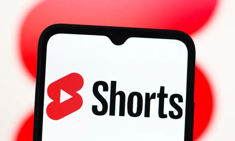 YouTube Shorts logo displayed on a smartphone screen against a blurred red background.