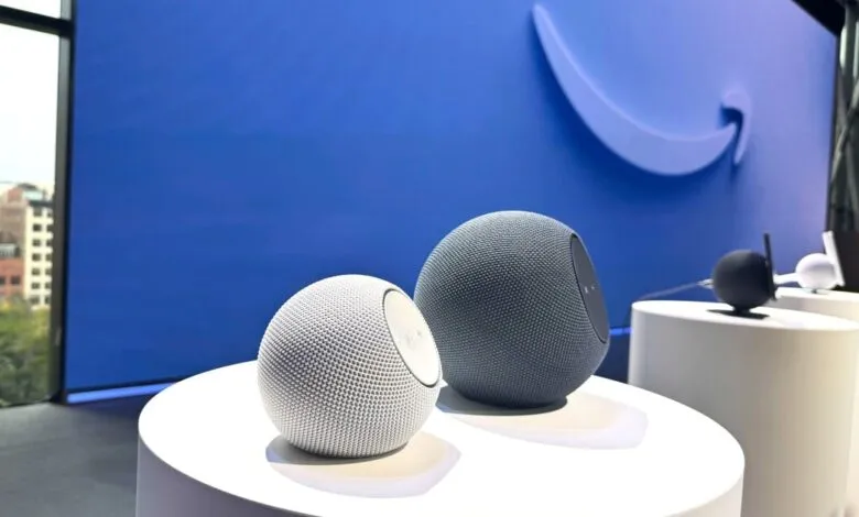 Two spherical smart speakers, one white and one gray, displayed on white pedestals.