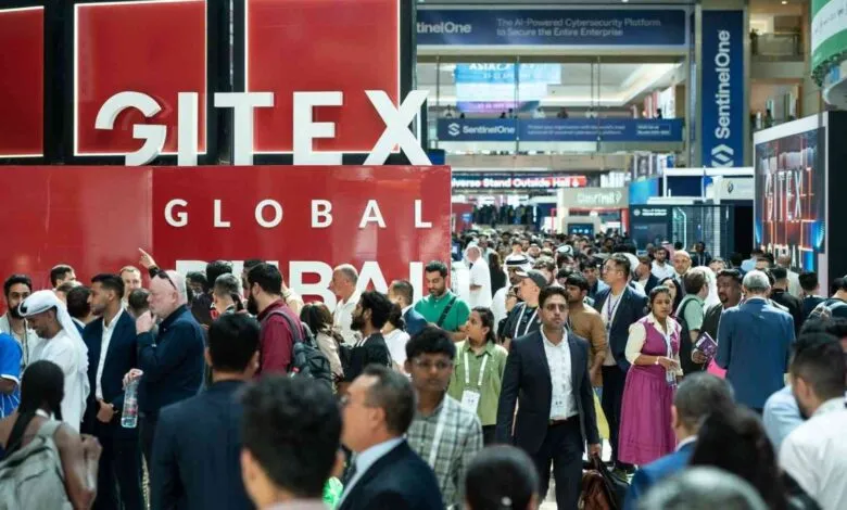 Crowd of people walking past a large GITEX GLOBAL sign at a technology exhibition.
