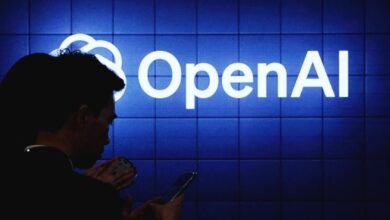 Silhouettes of people looking at the glowing white OpenAI logo on a blue tiled screen.