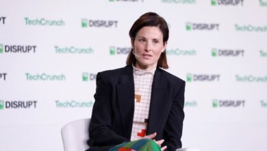 Woman in a black blazer and patterned shirt speaking on stage at TechCrunch Disrupt.