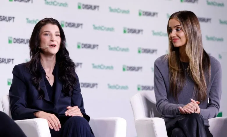 Two women speaking on a panel at TechCrunch Disrupt, with a backdrop of the event logo.