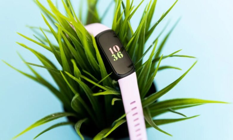 Fitbit Inspire 3 fitness tracker with a light purple band nestled in green grass.