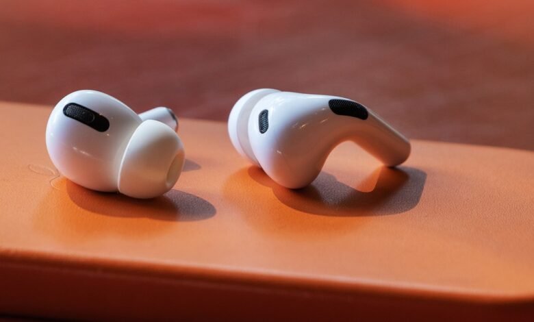 Close-up of white Apple AirPods Pro 2 earbuds on an orange surface.