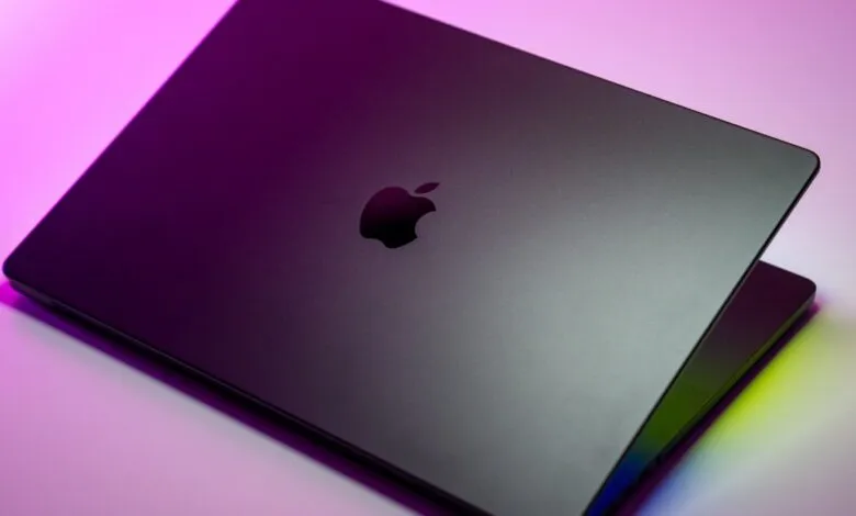 Close-up of a dark gray Apple MacBook Pro laptop with the illuminated Apple logo.