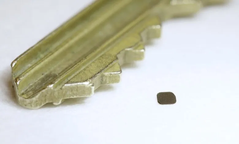 Close-up of a brass key's teeth next to a tiny, dark microchip.