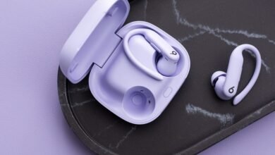 Pair of lavender Powerbeats Pro earbuds with charging case on a marble tray.