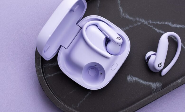 Pair of lavender Powerbeats Pro earbuds with charging case on a marble tray.