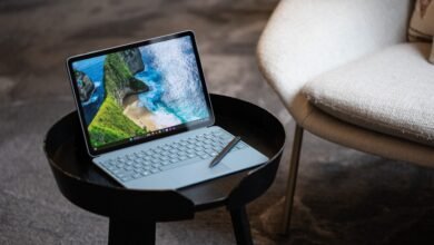A light blue Microsoft Surface Pro laptop with a stylus rests on a black side table.
