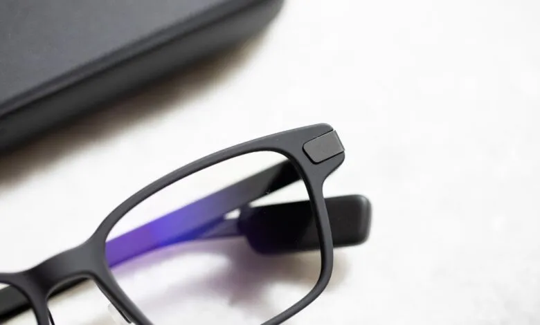 Close-up of matte black eyeglasses with a protective case in the background.