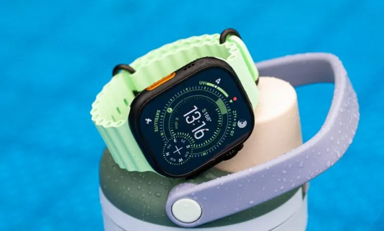 Apple Watch Ultra with a light green band rests on a water bottle, showing a compass face.