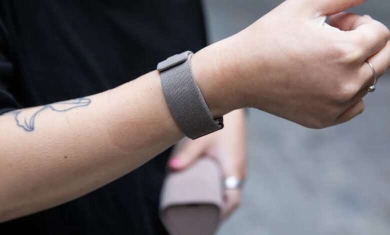 Close-up of a person's arm wearing a grey fabric fitness tracker band.