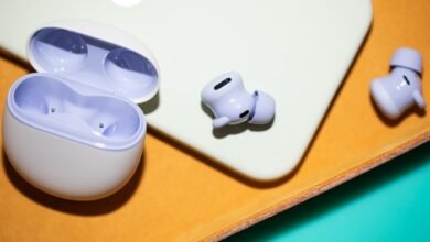 Lavender wireless earbuds and charging case on a textured surface.