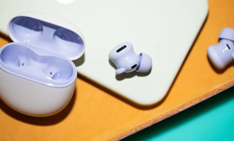 Lavender wireless earbuds and charging case on a textured surface.