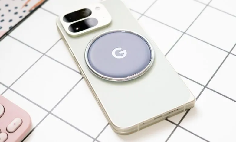 Close-up of a light green smartphone with a circular Google charger attached to its back.