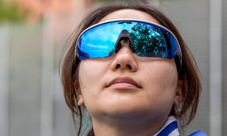 Close-up of a woman wearing large, reflective blue sports sunglasses.