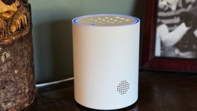 White cylindrical ADT smart home device with blue light ring and keypad on top.