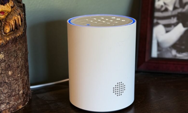 White cylindrical ADT smart home device with blue light ring and keypad on top.