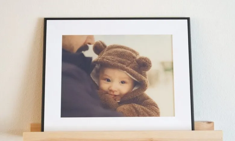A framed photo of a baby in a bear costume being held by a person.