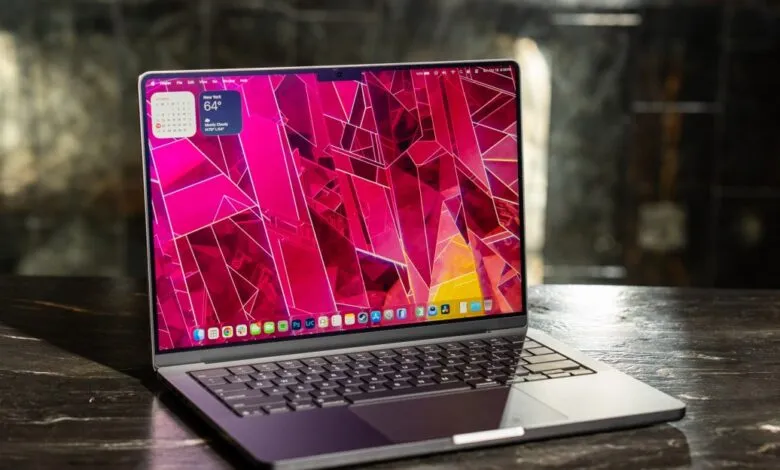 Close-up of a silver Apple MacBook Pro laptop with a vibrant pink abstract wallpaper.