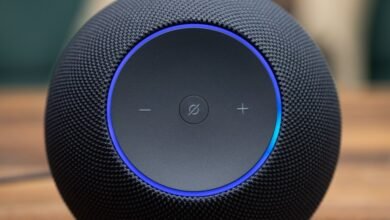 Close-up of a black smart speaker with a blue light ring and touch controls.
