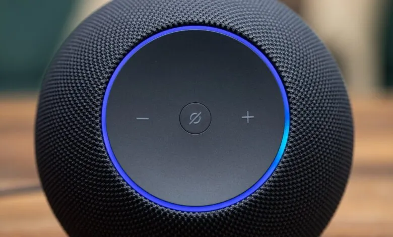 Close-up of a black smart speaker with a blue light ring and touch controls.