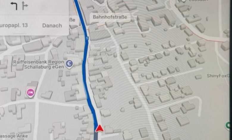 Close-up of a car's navigation screen showing a 3D map with a blue route.