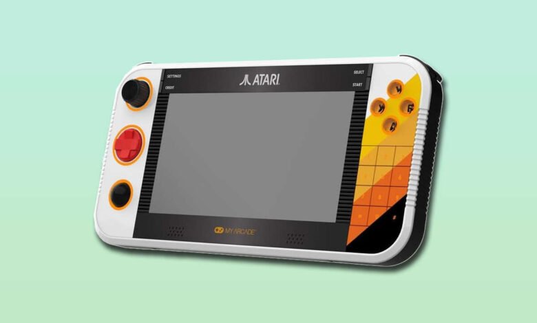 Close-up of a white portable Atari gaming device with a gray screen and colorful buttons.