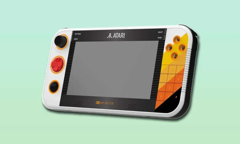 Close-up of a white portable Atari gaming device with a gray screen and colorful buttons.