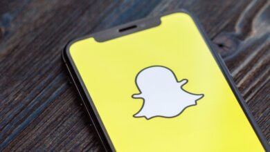 Close-up of a smartphone displaying the Snapchat logo on a bright yellow screen.