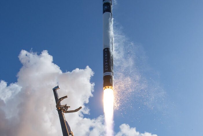 Rocket launch with bright flames and smoke against a blue sky with clouds.