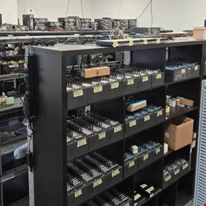 Shelves filled with electronic components and server racks in a storage room.