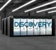 Server racks in a modern data center with a large screen displaying 'DISCOVERY'.