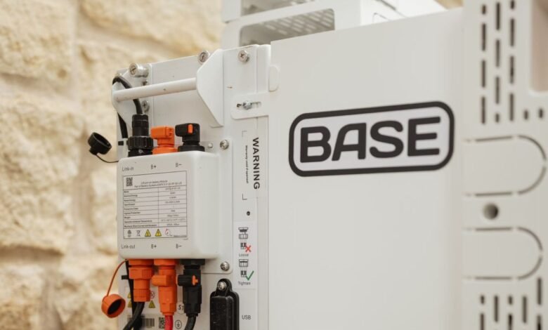 Close-up of a white BASE battery storage unit with visible wiring and warning labels.