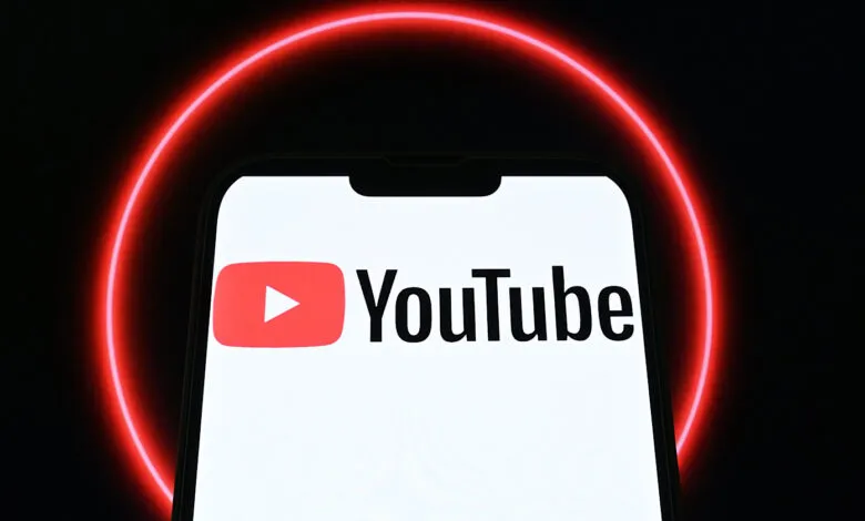 The YouTube logo displayed on a smartphone screen, with a red neon circle in the background.