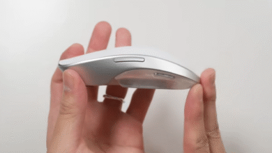 Close-up of a white and silver computer mouse held by two hands.