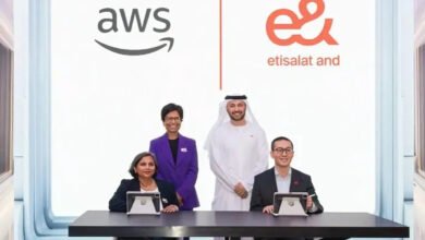 Four individuals pose in front of AWS and Etisalat logos, signifying a partnership.
