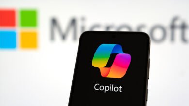 Smartphone displaying the Copilot AI logo with the Microsoft logo blurred in the background.