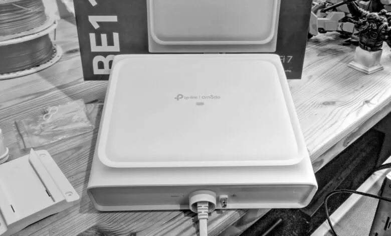 TP-Link Omada access point with network cable connected, alongside mounting hardware and spools of wire.