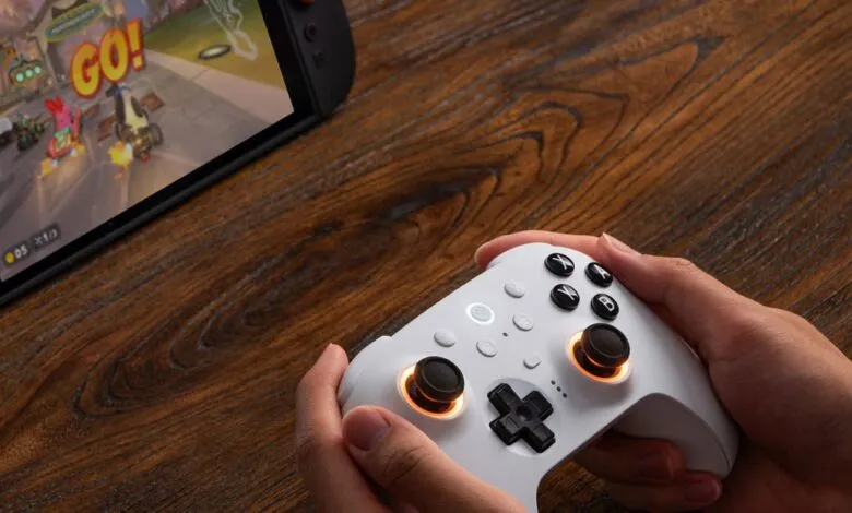 Hands holding a white gaming controller playing a racing game on a Nintendo Switch.