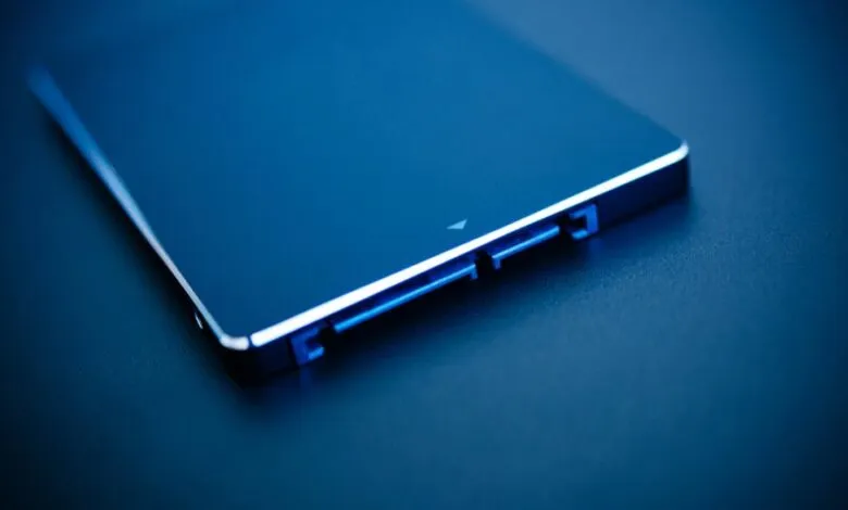 Close-up of a sleek, dark blue SSD with blue illuminated SATA connectors.