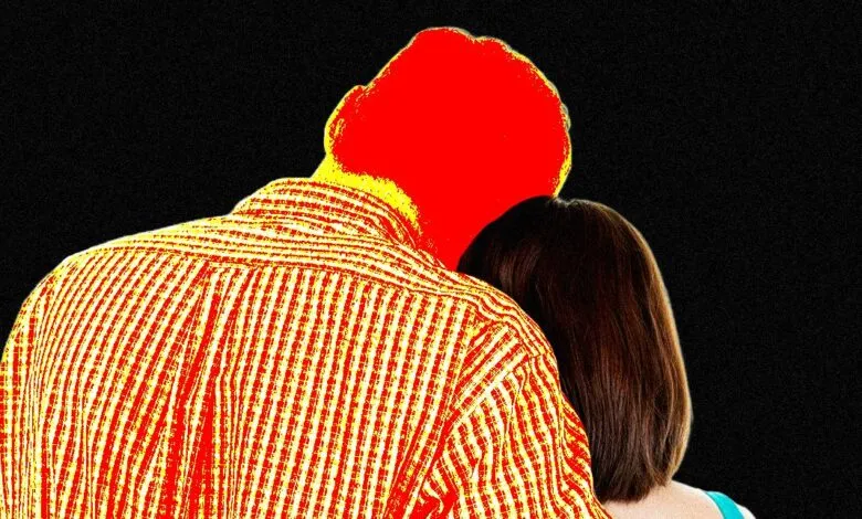 Close-up of a person in a red and yellow striped shirt embracing another person from behind.
