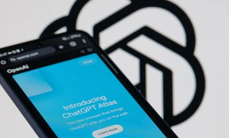 Smartphone displaying the OpenAI ChatGPT Atlas browser interface with the OpenAI logo in the background.