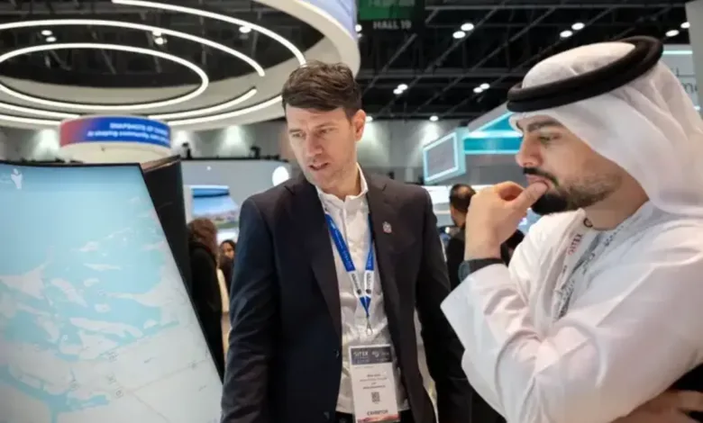 Two men examining a large interactive map display at a technology exhibition.