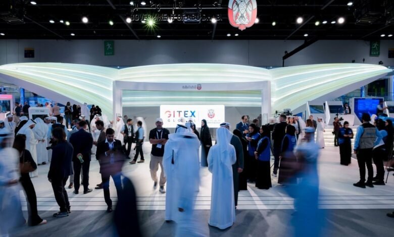 People at the GITEX Global technology exhibition in Dubai, with a large display and government branding.